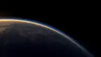 Sunrise grazes Earth's curving horizon, warm gold rim fading into cobalt over scattered clouds, Blue Planet wallpaper