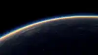 Earth's horizon arcs across a black sky, golden atmospheric rim above a dark continent dotted with city lights, Blue Planet wallpaper