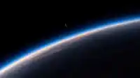Earth's blue atmospheric arc sweeps below a slim crescent moon hanging in black space, serene Blue Planet wallpaper