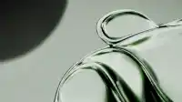 Tall standing loop of emerald glass like an elegant glass handle on pale studio ground, dim shadow upper left, Liquid Emerald wallpaper