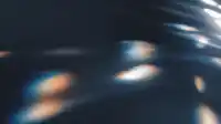 Strong diagonal beams sweep down onto a dark grained surface, blue and amber prism flare at center, Prism Leaks wallpaper